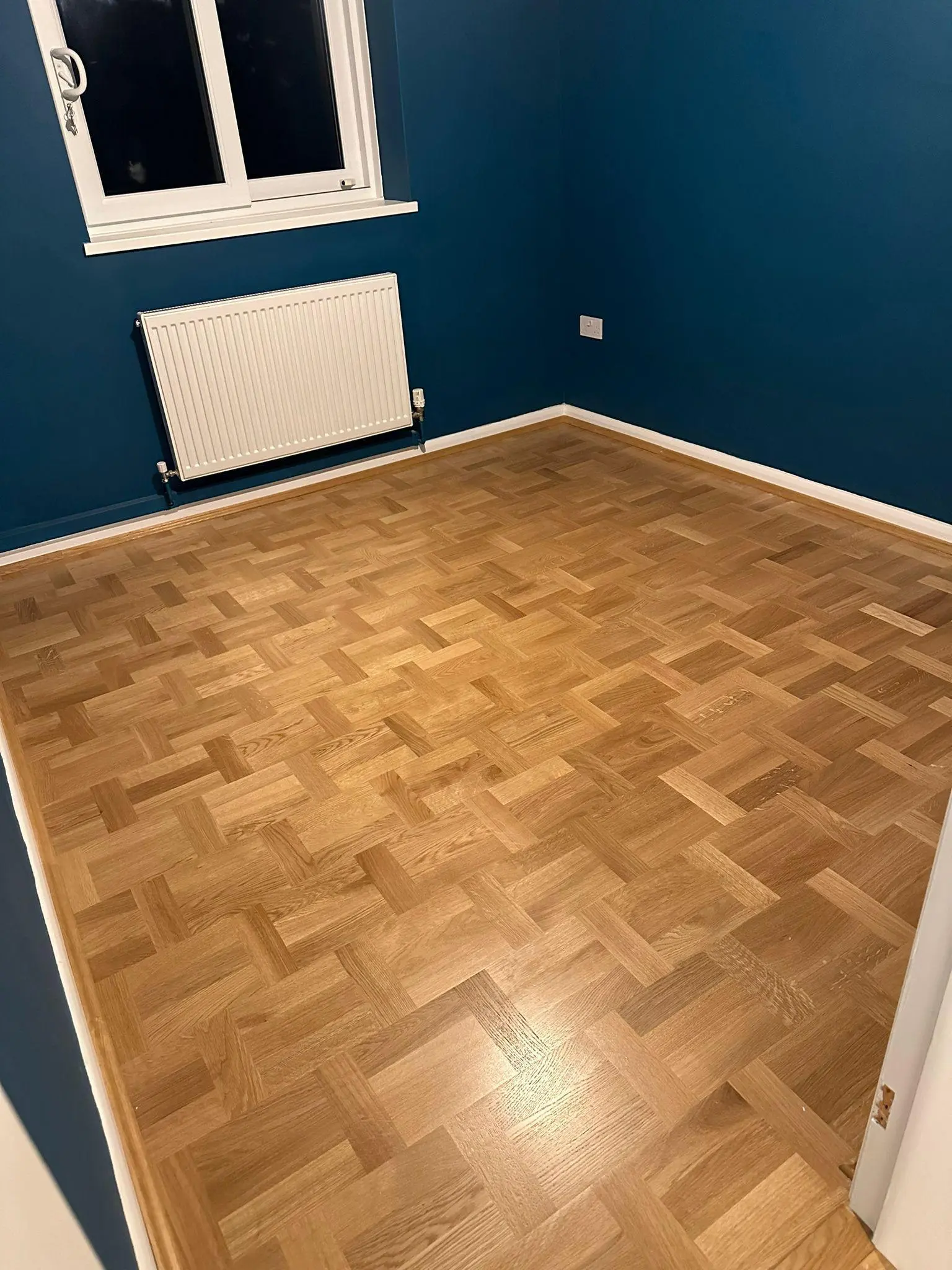 Oak basketweave parquet flooring in a navy-blue bedroom