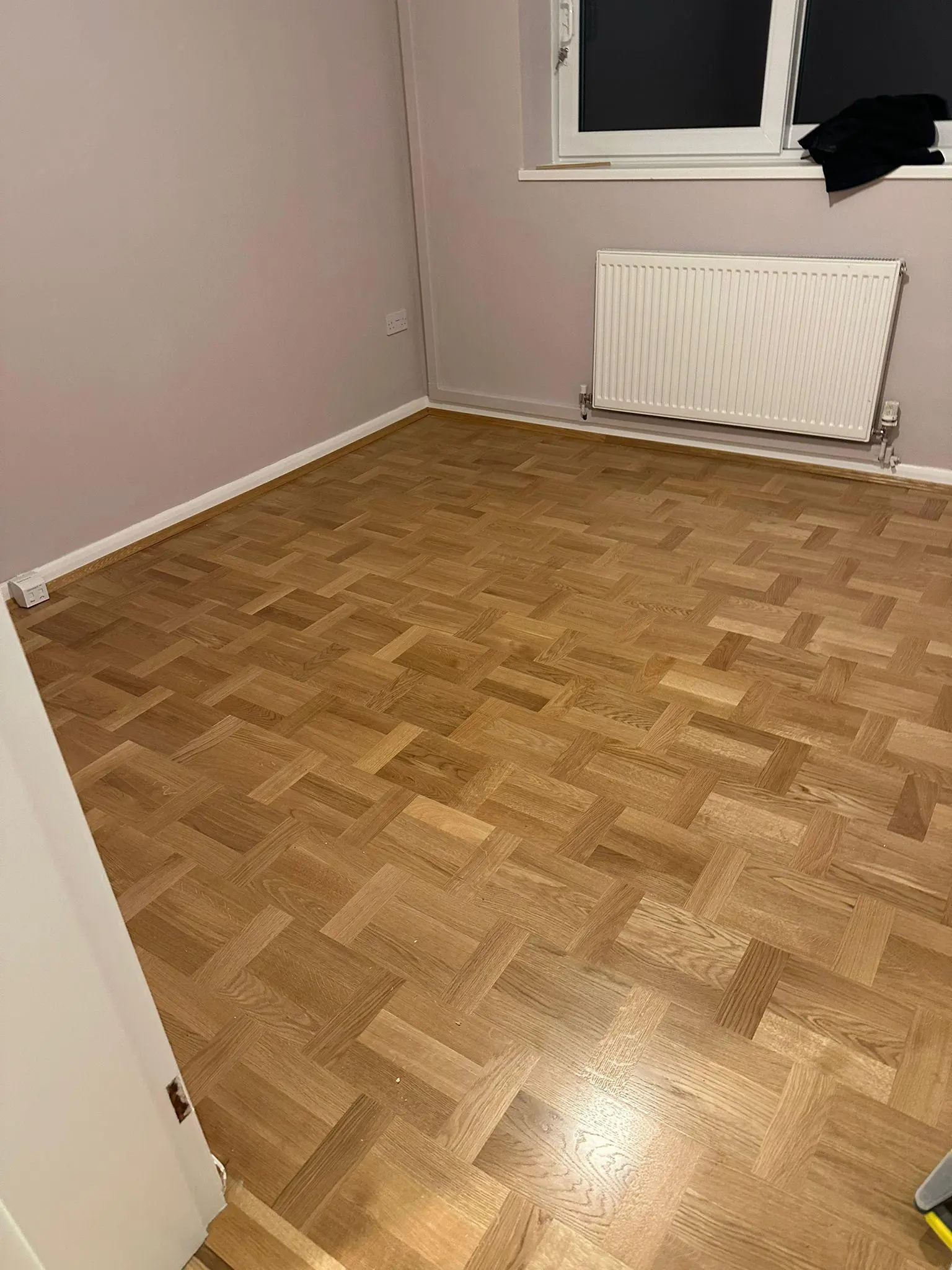 Oak basketweave parquet flooring in a pink-walled bedroom