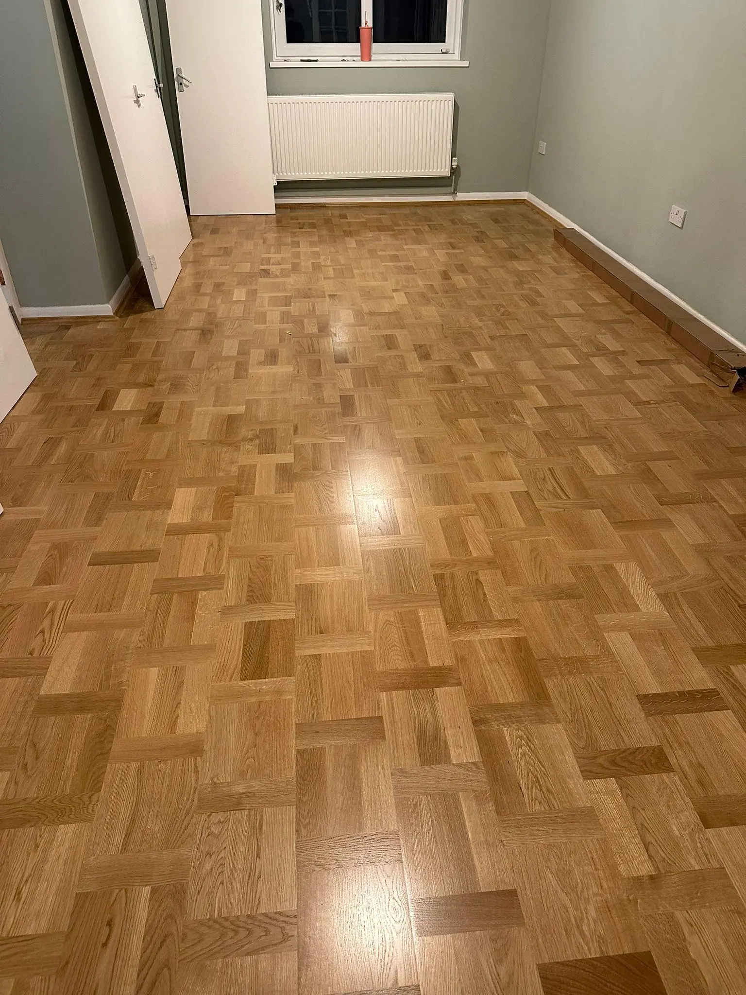 Oak basketweave parquet flooring in a sage-green room