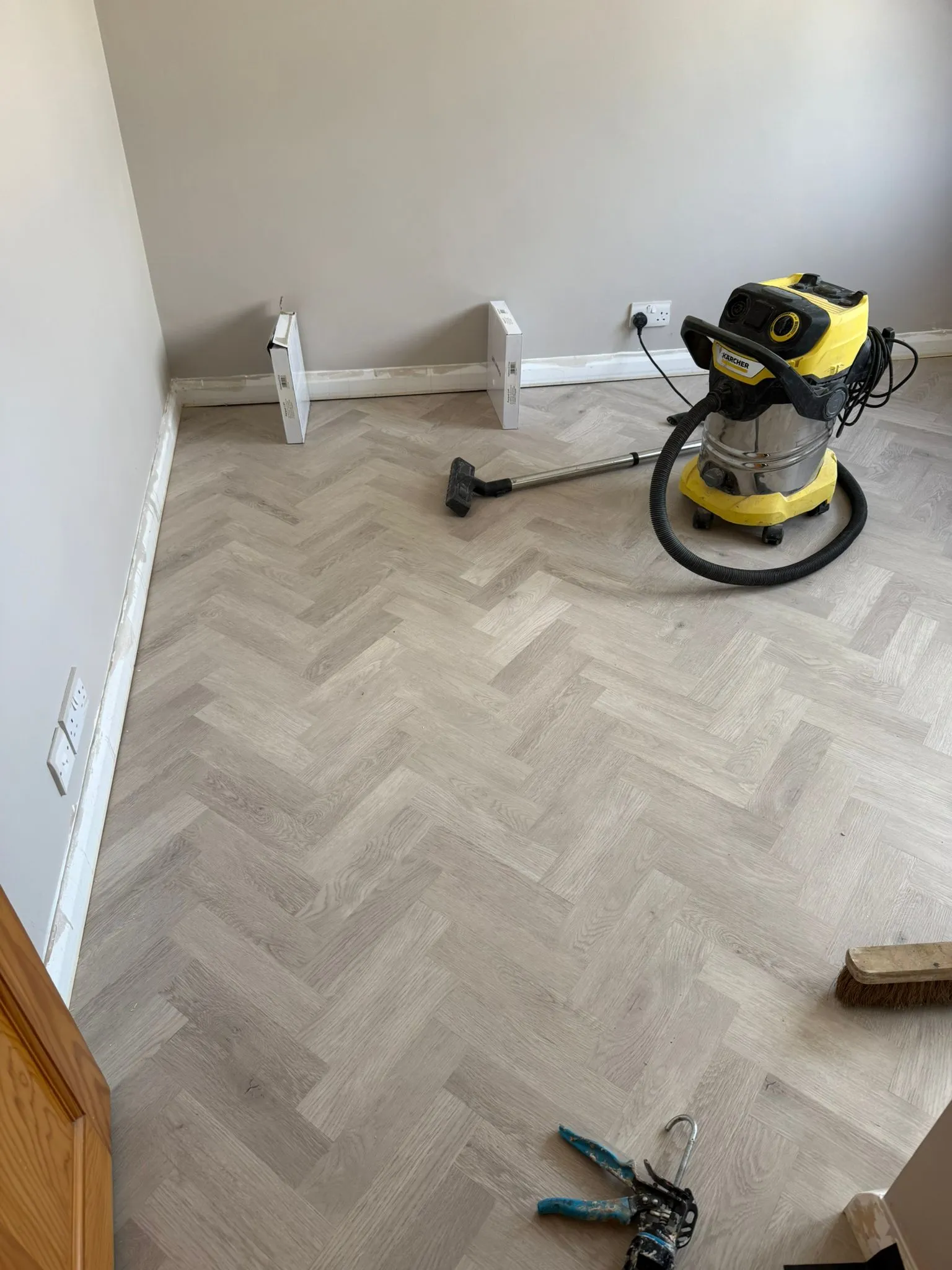 Light grey herringbone LVT flooring laid across a living room