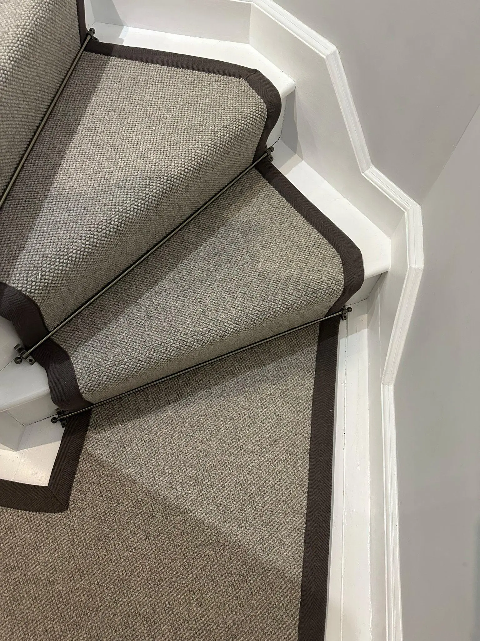 Beige loop-pile stair runner with dark brown border fitted on a white-painted staircase
