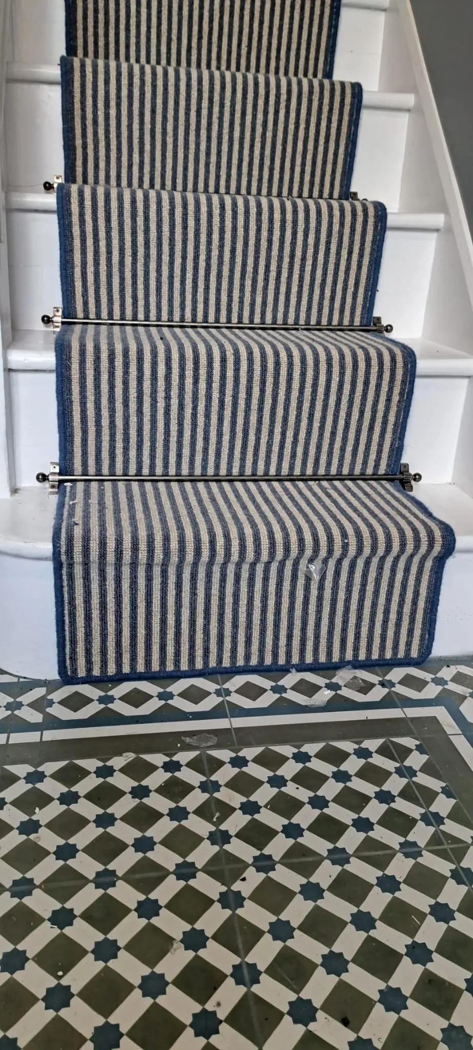 Blue striped stair runner meeting a Victorian tiled hallway floor