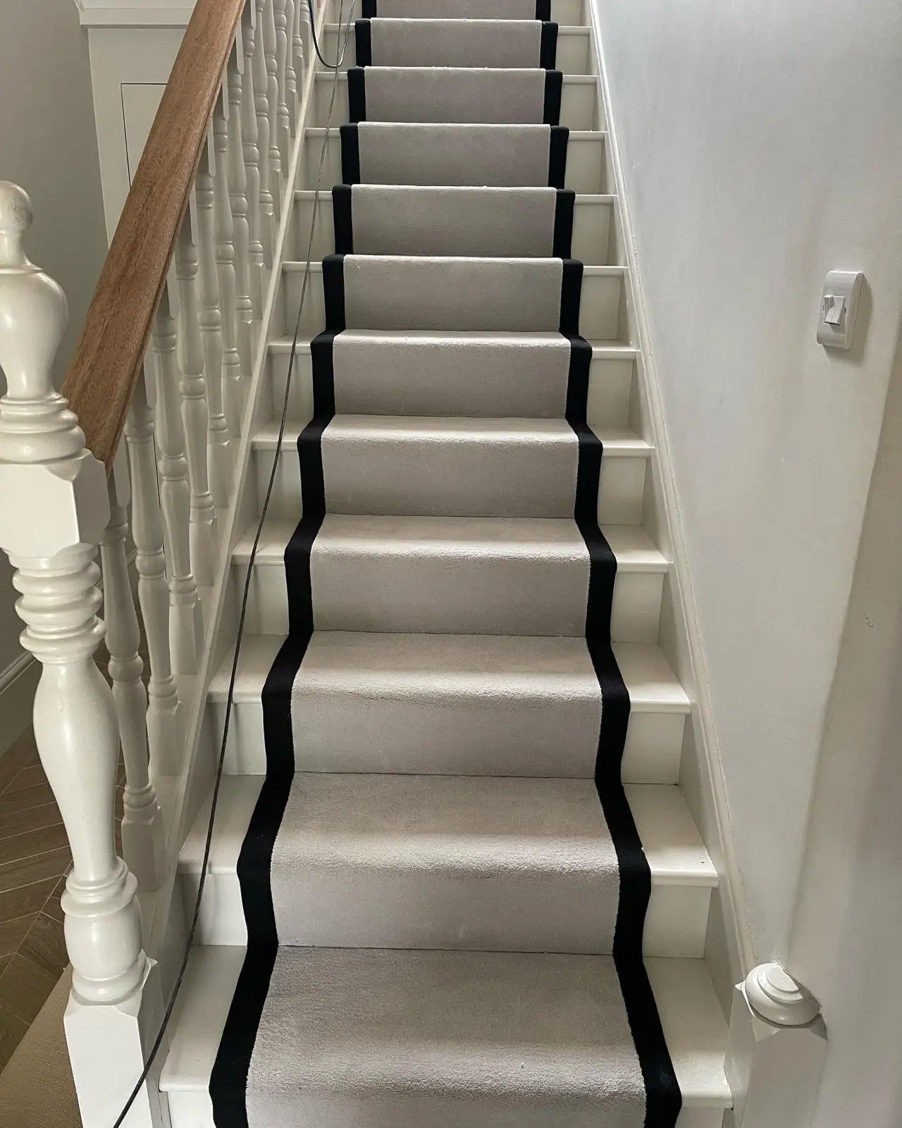 Grey stair runner with black border fitted on a white-painted staircase