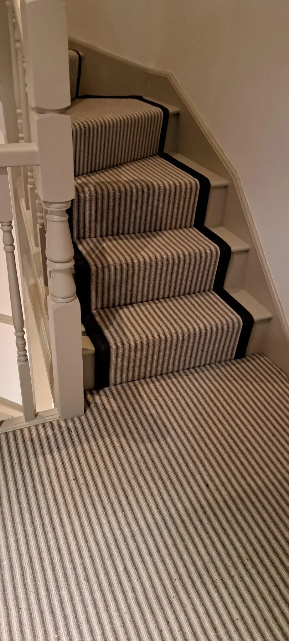 Grey striped stair runner with black border fitted on winder stairs